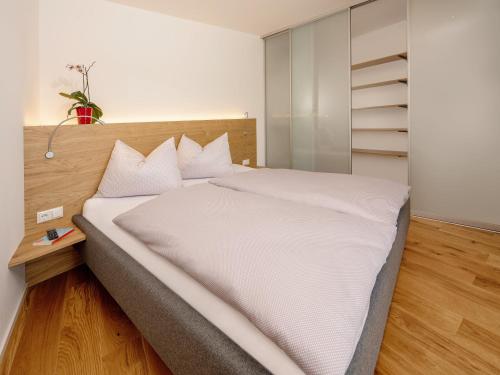 a bedroom with a large bed with white sheets at Brunnwirt ESSEN & WOHNEN in Fuschl am See