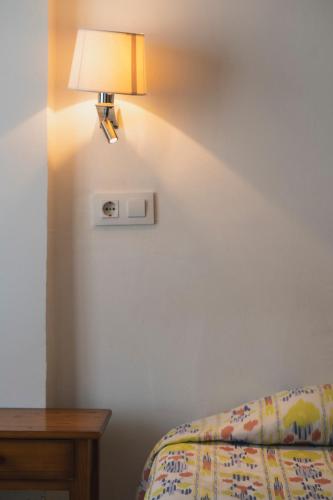 a lamp on a wall next to a bed and a table at Hotel Amic Can Pastilla in Can Pastilla