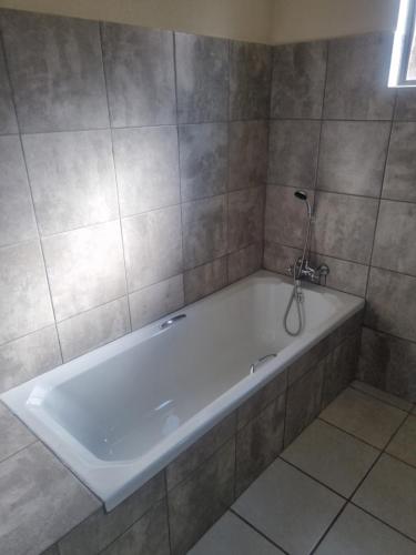 a white bath tub in a tiled bathroom at Jazreel b&b in Vanderbijlpark