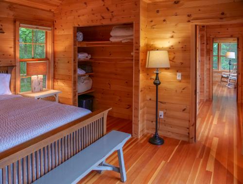 a bedroom in a log cabin with a bed and a lamp at Finlays Cove on the Lake in Colchester