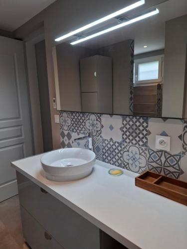 a bathroom with a sink and a large mirror at Le petit Clémenceau in Pessac