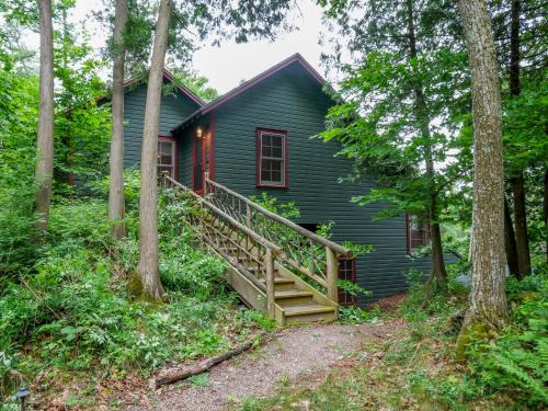 a green house in the woods with a wooden staircase at Finlays Cove on the Lake in Colchester