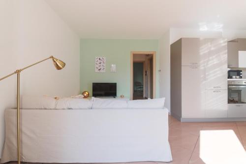 a living room with a white couch and a lamp at Appartamenti Orchidea e Glicine in Sommacampagna