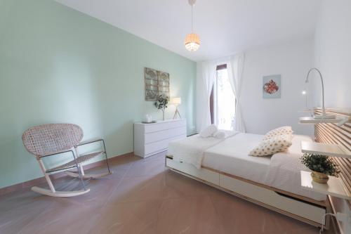 a white bedroom with a bed and a chair at Appartamenti Orchidea e Glicine in Sommacampagna