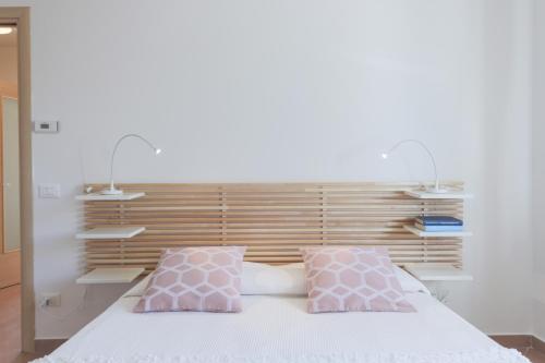 a bedroom with a bed with two pink pillows at Appartamenti Orchidea e Glicine in Sommacampagna