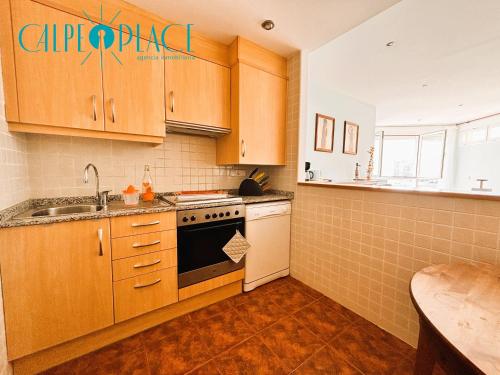 a kitchen with wooden cabinets and a sink and a stove at Kenya 1ª Linea in Ifach