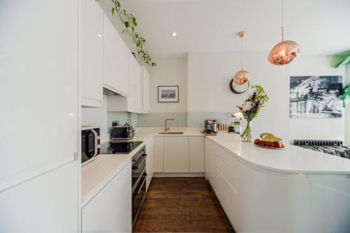 a kitchen with white cabinets and a counter top at Primrose Boutique Home in London