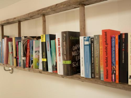 a row of books on a wooden shelf at Brunnwirt ESSEN & WOHNEN in Fuschl am See