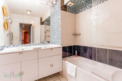 une salle de bain blanche avec une baignoire et un lavabo dans l'établissement Brunhes Toulouse - CI - Spacieux 3 chambres Pkg Métro St Cyprien, à Toulouse
