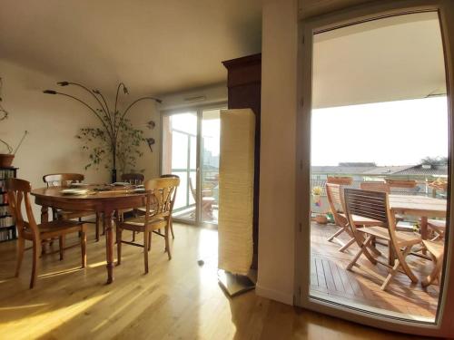 une salle à manger avec une table et des chaises et un balcon dans l'établissement Brunhes Toulouse - CI - Spacieux 3 chambres Pkg Métro St Cyprien, à Toulouse