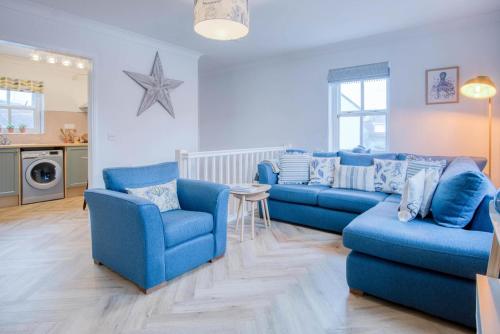 a living room with two blue couches and a table at Kilmore House - 2 Bedroom Apartment - Tenby in Tenby