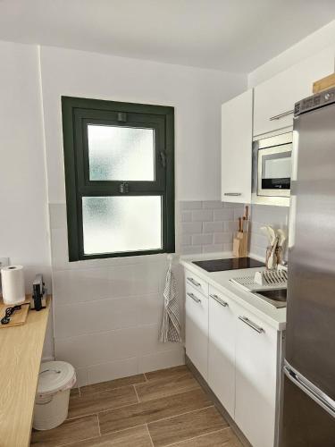 a kitchen with white cabinets and a window at Canaima 112 Puerto Rico in Puerto Rico de Gran Canaria