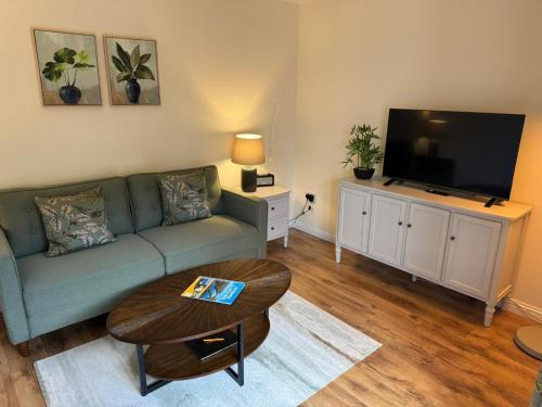 a living room with a green couch and a flat screen tv at 20a, By The Ness in Inverness