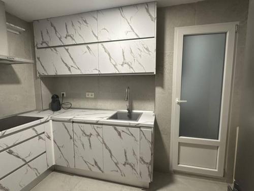 una cucina bianca con lavandino e porta di Feria Home ad Albacete