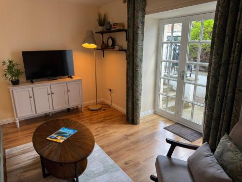 a living room with a television and a table at 20a, By The Ness in Inverness