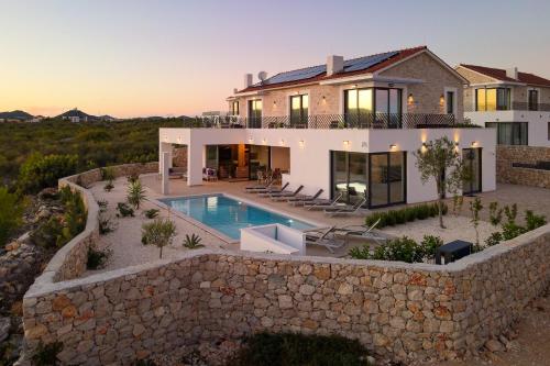 a villa with a swimming pool and a stone wall at Villa Liliana Vodice in Vodice