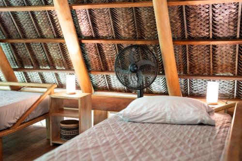 a room with a bed and a fan and two candles at Canto Tayrona Ecolodges in Buritaca
