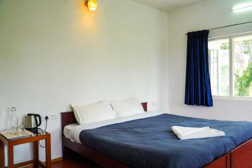 a bedroom with a bed with a blue blanket and a window at HappyHuts at Green valley view in Kodaikānāl