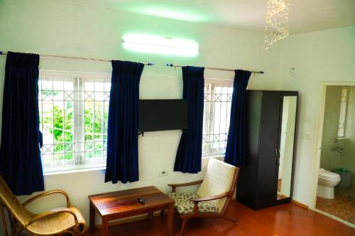 a living room with blue curtains and a table and chairs at HappyHuts at Green valley view in Kodaikānāl