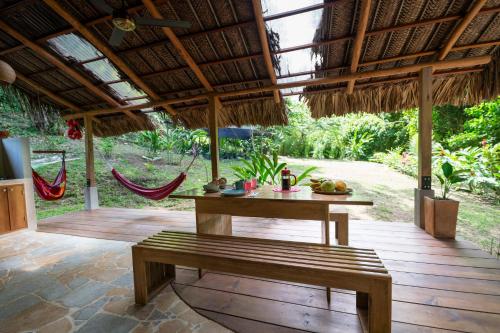 a patio with a table and a bench and hammocks at Canto Tayrona Ecolodges in Buritaca