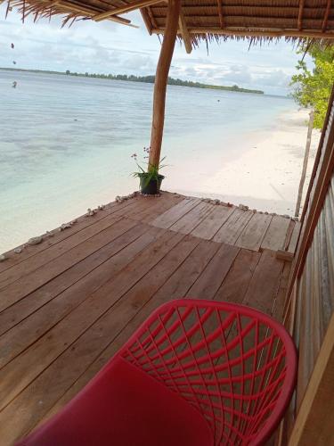 a red chair sitting on a wooden deck next to the beach at Fam Homestay in Fam