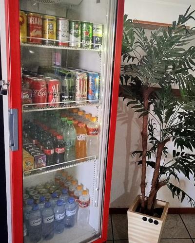 an open refrigerator filled with drinks and a potted plant at Hotel Xapuri in Peruíbe