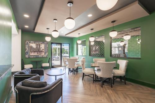 a restaurant with green walls and tables and chairs at Hotel Alice in Atlantic Beach