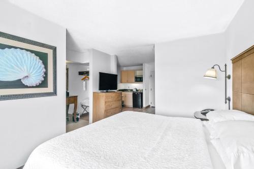 a bedroom with a white bed and a kitchen at Hotel Alice in Atlantic Beach