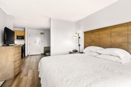 a bedroom with a large white bed and a flat screen tv at Hotel Alice in Atlantic Beach