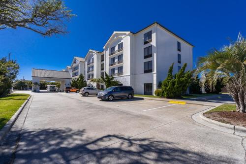 a large white building with cars parked in a parking lot at Hotel Alice in Atlantic Beach