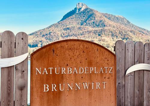 a sign on a fence with a mountain in the background at Brunnwirt ESSEN & WOHNEN in Fuschl am See