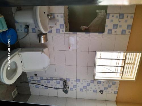 a bathroom with a toilet and a window in it at Pearl Motel Wing in Mukono