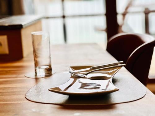 a table with a plate and a glass on it at Brunnwirt ESSEN & WOHNEN in Fuschl am See