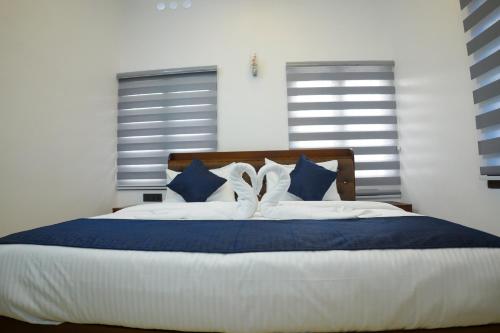 a bedroom with a bed with blue and white pillows at Teak and Lake Homestay in Thekkady
