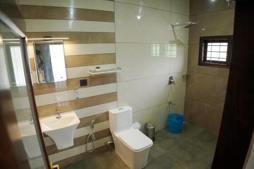 a bathroom with a toilet and a sink at Teak and Lake Homestay in Thekkady