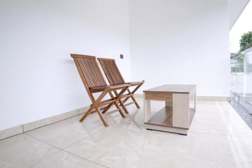 two wooden chairs and a table in a room at Teak and Lake Homestay in Thekkady