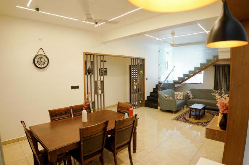 a dining room and living room with a table and chairs at Teak and Lake Homestay in Thekkady