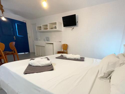 a white bedroom with two towels on a bed at Argo-Milos in Adamas