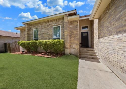 a brick house with a green lawn in front of it at Cozy Brick Home in San Antonio