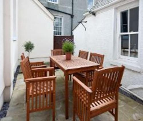a wooden table and chairs with a potted plant on a patio at Beautiful Listed Townhouse in Beaumaris in Beaumaris