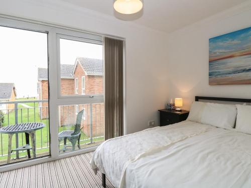 een slaapkamer met een bed en een groot raam bij 102 Waterside Park in Lowestoft