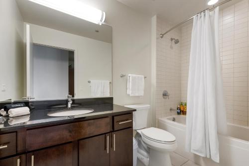 a bathroom with a sink and a toilet and a mirror at K2 Sky High Apartments with Stunning Chicago Views in West Loop in Chicago
