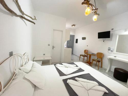 a white bedroom with a bed and a table at Argo-Milos in Adamas