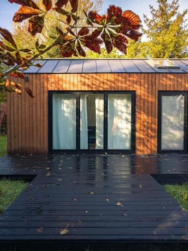 a house with a wooden deck in front of it at W Ogrodzie Dla Gości in Sasino