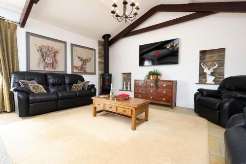 a living room with black leather furniture and a coffee table at Little Barn at East Down in Cowbridge