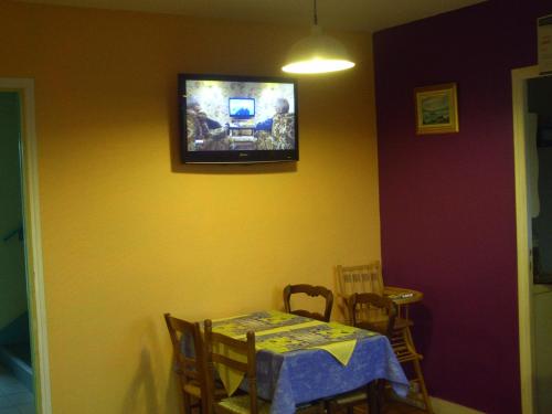 a dining room with a table and a tv on the wall at Hôtel l'Eden in Brix