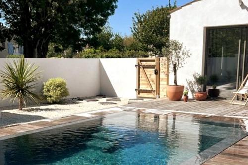 - une piscine dans une arrière-cour dotée d'un mur blanc dans l'établissement Villa familiale avec piscine chauffée, à Périgny