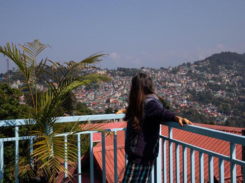 a woman standing on a balcony looking at a city at Hills Tale Backpackers Hostel in Kalimpong