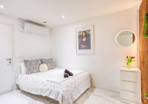une chambre blanche avec un lit et un miroir dans l'établissement Évasion Urbaine Studio Cozy avec Terrasse et Parking, à 10 Minutes de Paris Gare du Nord, à Montmagny