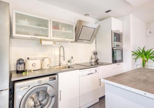 une cuisine blanche avec une machine à laver à l'intérieur dans l'établissement Évasion Urbaine Studio Cozy avec Terrasse et Parking, à 10 Minutes de Paris Gare du Nord, à Montmagny